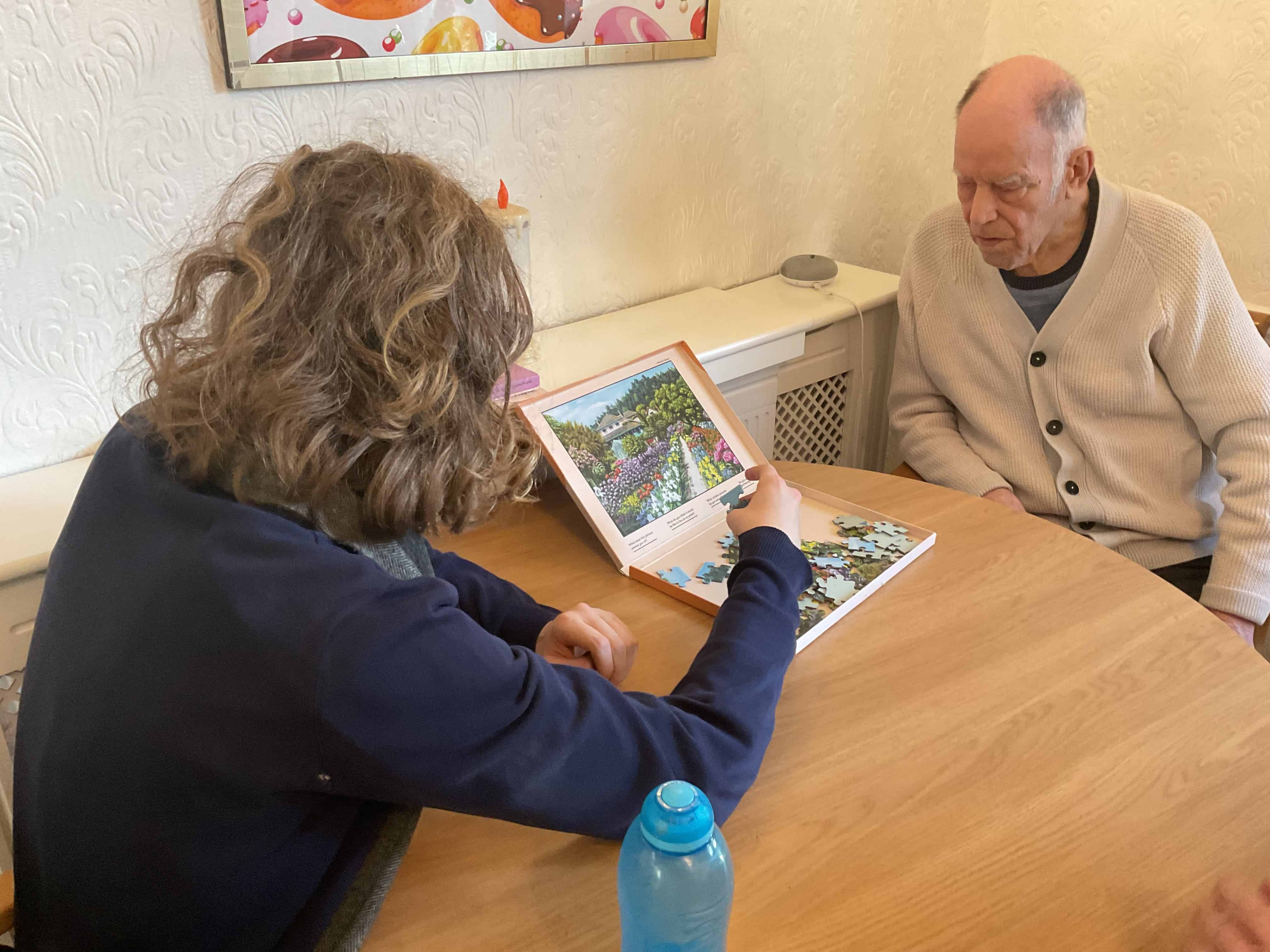 A student from Priestnall School works on a jigsaw with a resident from Priestnall Court Residential Home.