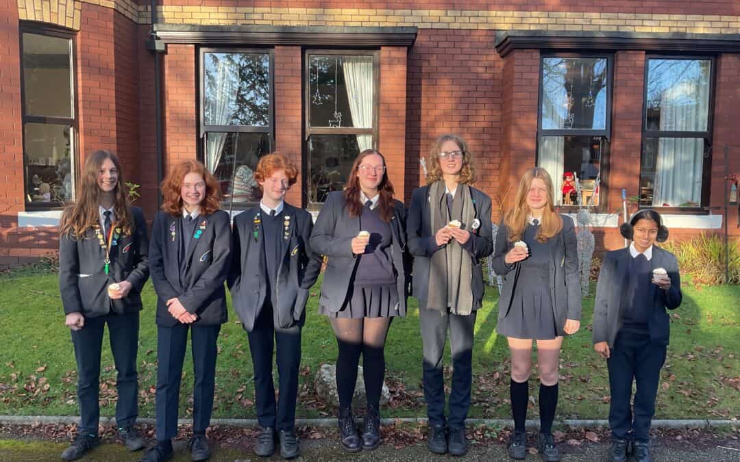 Students from the School Council at Priestnall School stand outside of Priestnall Court Residential Home holding cupcakes