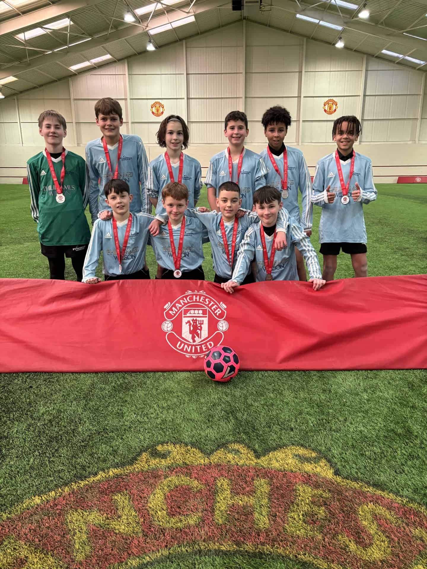 The Priestnall School Boys team pose behind a Manchester United banner on the pitch after winning the regional qualifiers of the Manchester United Academy Emerging Talent competition.