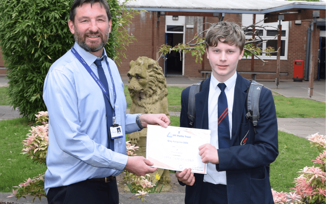 Priestnall School student holds certificate of merit with a maths teacher after success in UKMT Grey Kangaroo.