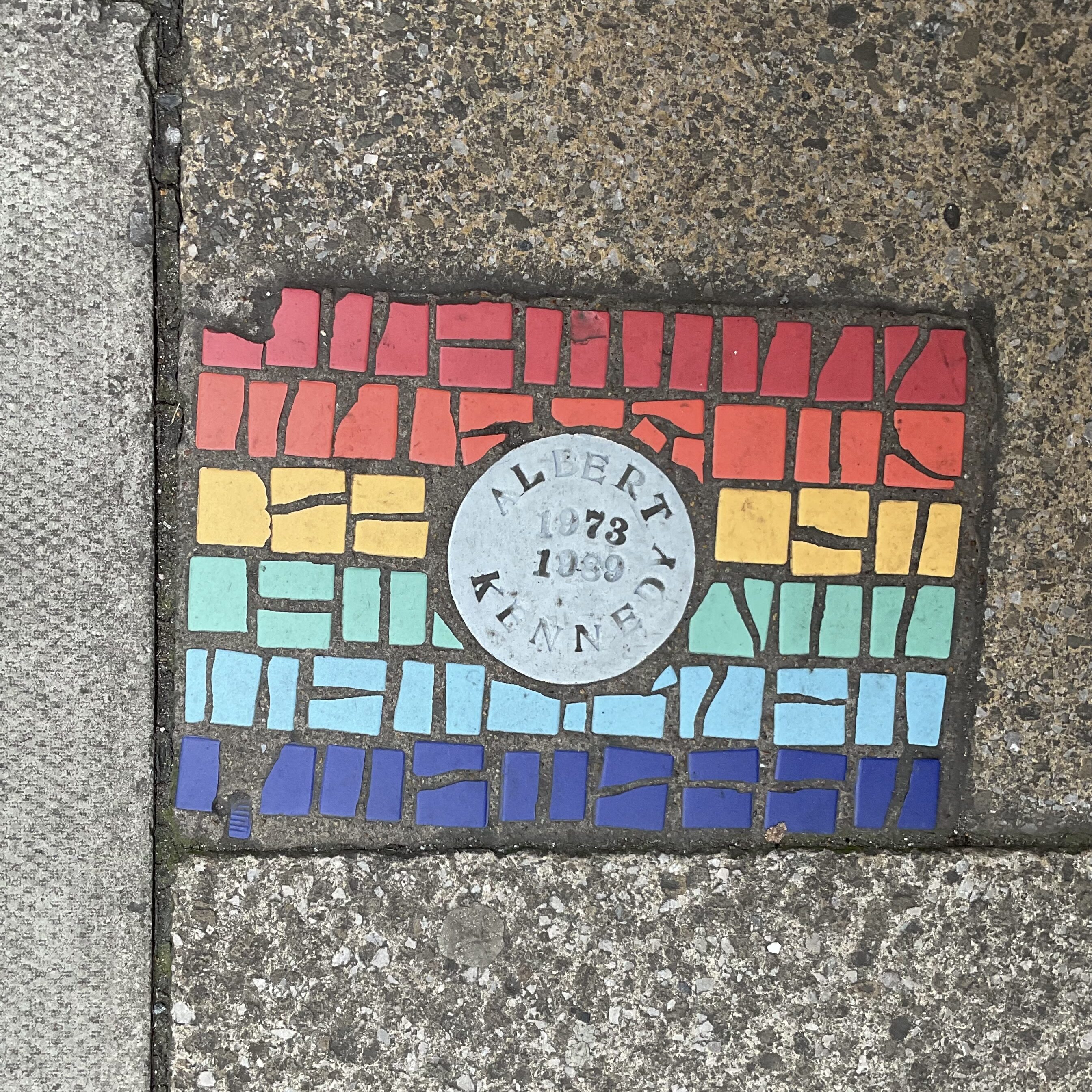 A rainbow mosaic on the pavement in Manchester City Centre.