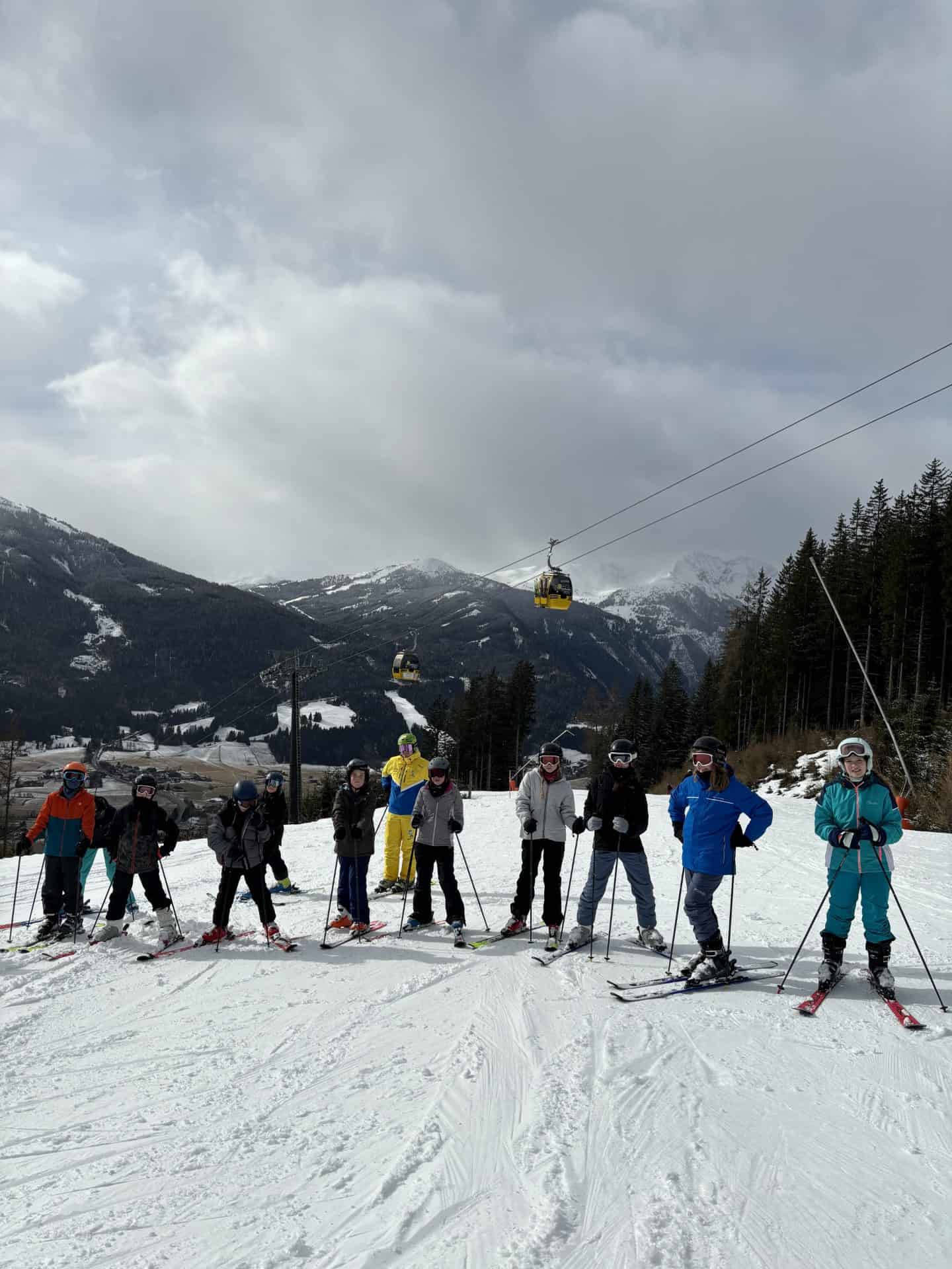 Students from Priestnall School stand in a line on a ski slope in Austria.